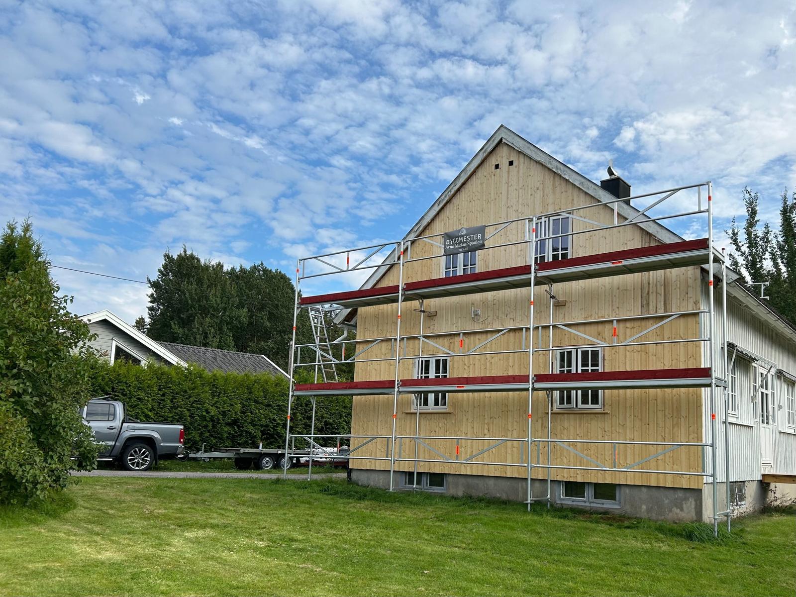 Gul bolig med stillas under fasadearbeid