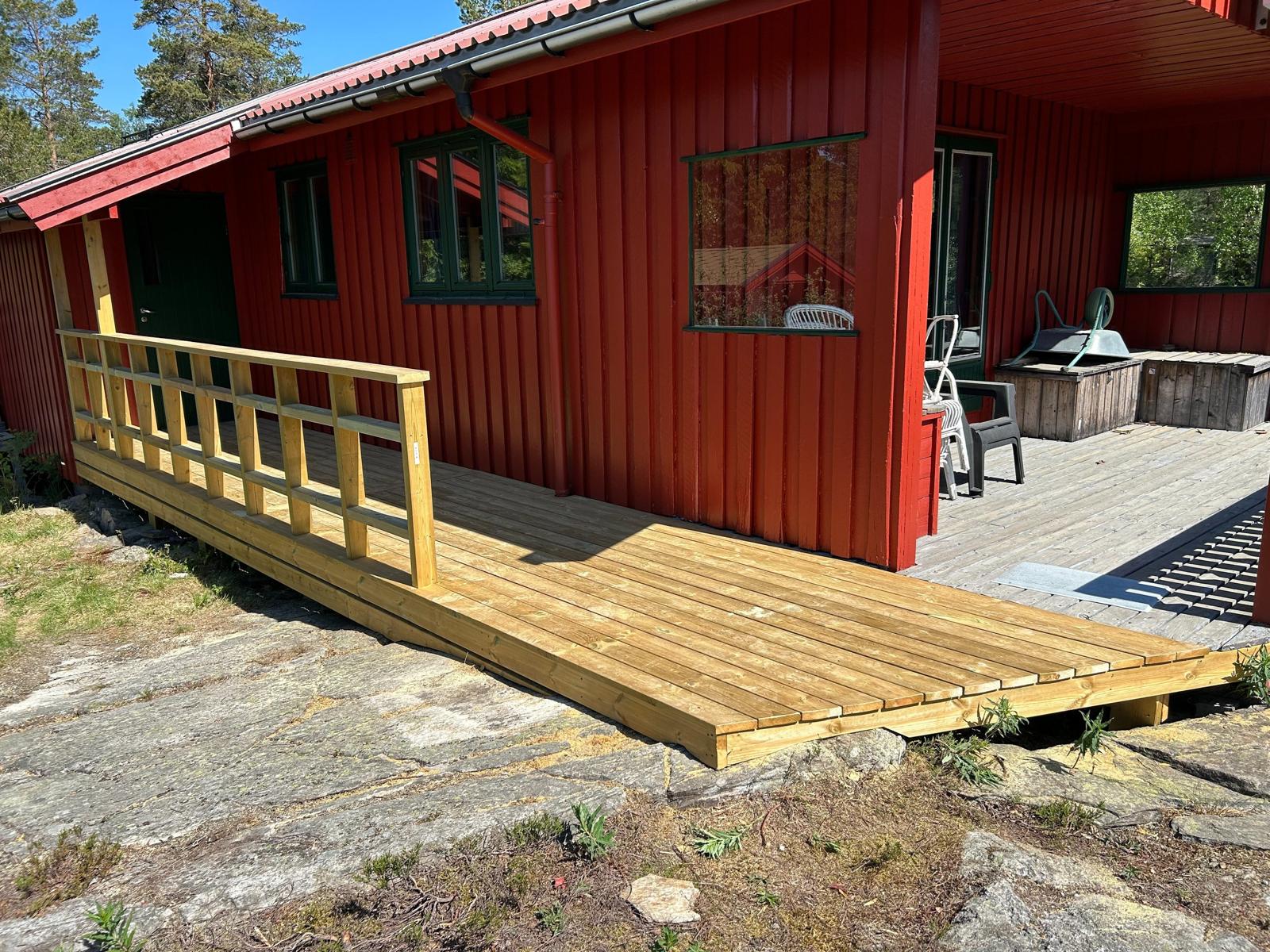 Rød hytte med ny platting og rekkverk i tre